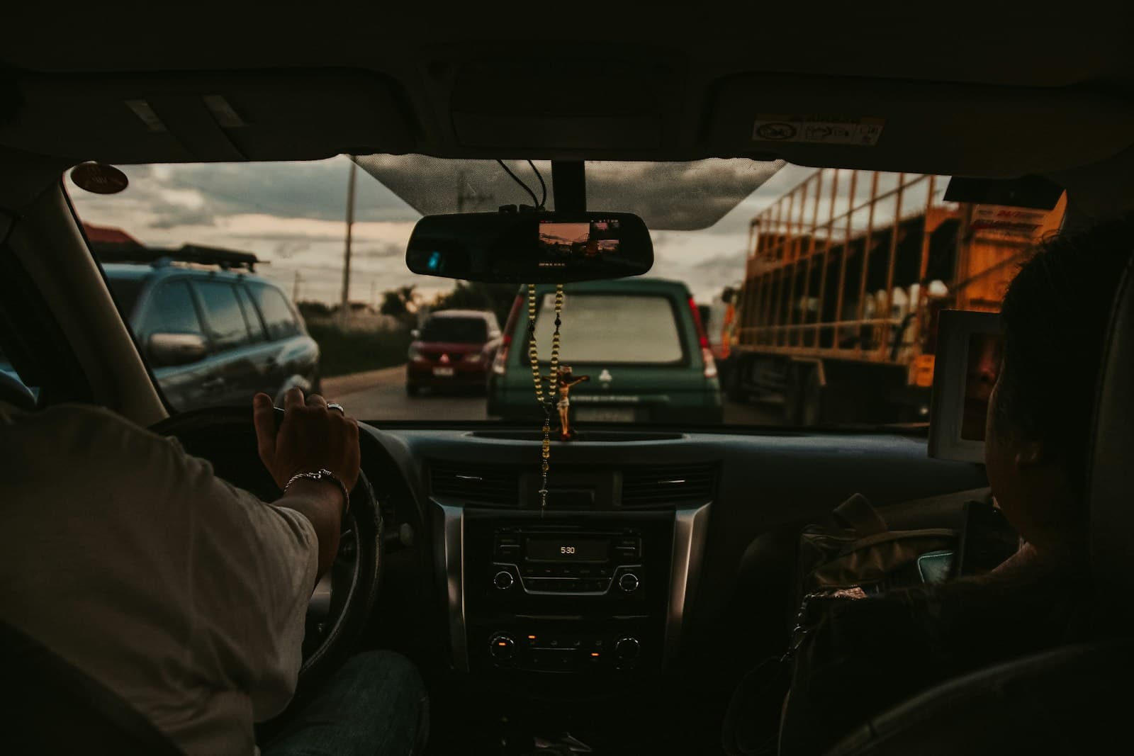 Driver navigating heavy traffic among cars and trucks on a busy highway at dawn