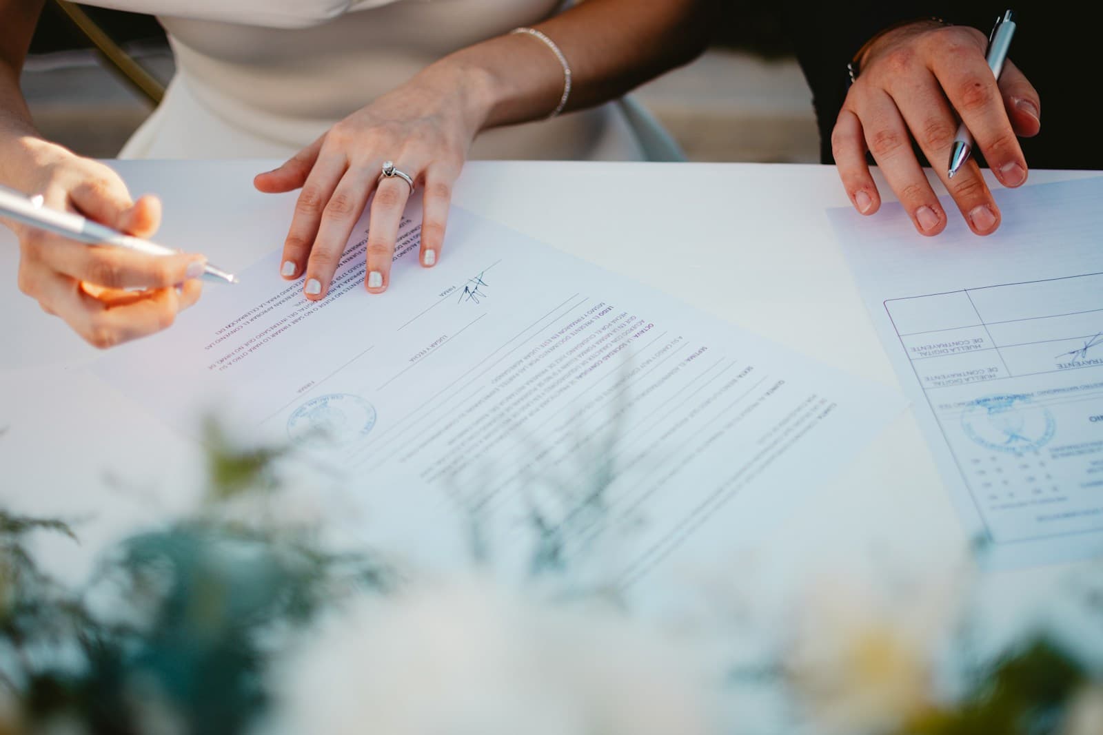 Two people at a table examining documents, one pointing out a section with a pen